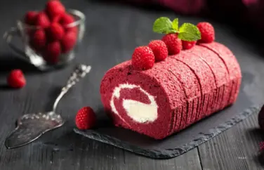 Delicious red velvet cake roll with cream filling, topped with strawberries and mint leaves