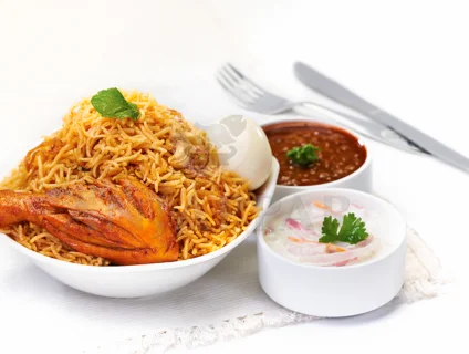 A dish of flavorful, aromatically steaming chicken briyani accompanied by gravy & onion raitha
