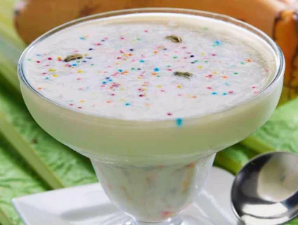 Bowl of creamy milk payasam served in glass bowl garnished colorful along with nuts.