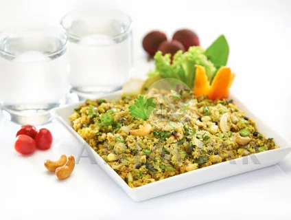 A special egg burji, served on a plate garnished with carrots, cashews, cilantro and water.