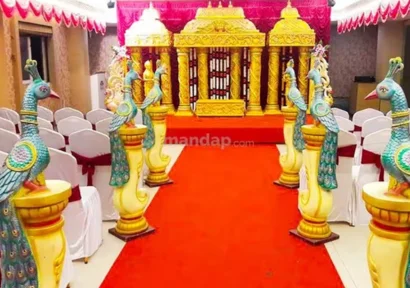 A banquet hall decorated for a wedding ceremony with a vibrant backdrop and peacock decorations.