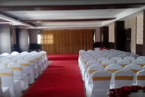 A banquet hall with a stage, backdrop, and neatly arranged chairs is perfect for any occasion.