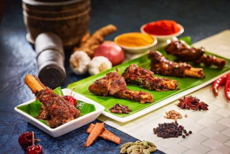 A plate of seasoned meat served on a green banana leaf, showcasing a delicious blend of spices.