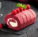 A mouthwatering roll of red velvet cake decorated with mint leaves and juicy raspberries.