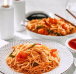Delicious steaming Chinese noodles served in a plate with two sauce and chopsticks on a table.