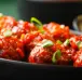 A platter of Gopi manchurian with a perfect texture garnished by green onions looks appealing.