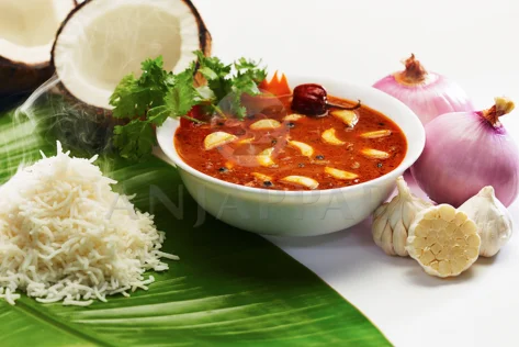Warm rice and a spicy bowl of garlic curry served on a banana leaf with coconut,garlic and onion.