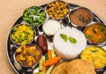 A platter of pooris & kurma, hot rice with sambar, rasam, and four varieties of veg side dishes.