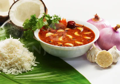 Hot rice and a tangy bowl of garlic curry with coconut, onion, and garlic presented on a banana leaf