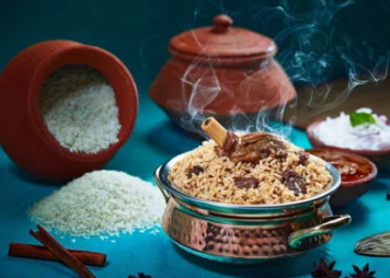 A bowl of flavorful spiced mutton biriyani rice with a variety of spices on a blue table
